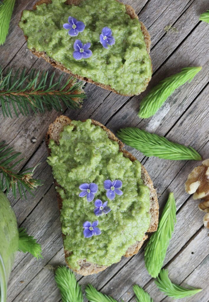 Spruce tip pesto spreaded on bread with flower decoration.